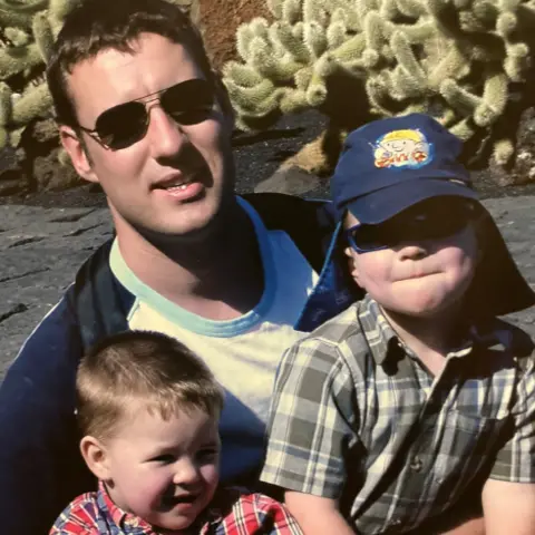 Wilson family Alistair Wilson wearing sunglasses holds his two little sons