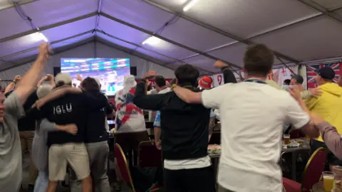 People are watching a TV screaming and jumping.