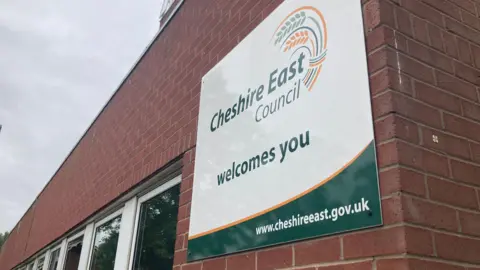 A sign saying Cheshire East Council welcomes you on the side of a building