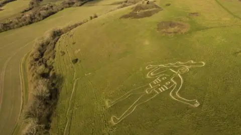 National Trust Images/PA Green hill covered in grass with naked chalk figure, the Cerne Abbas Giant carved into it.