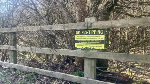 Photograph of a sign on a wooden fence in the Medlock Valley in Park Bridge - between Oldham and Tameside.