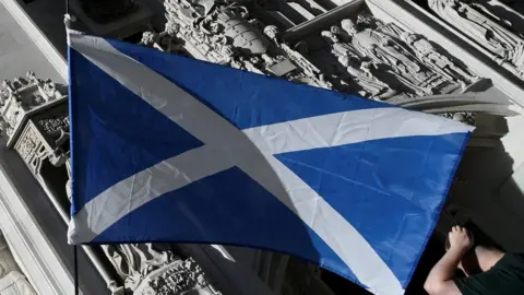 Reuters A Scottish Saltire flag is flown as pro-Scottish independence campaigners protest outside of the United Kingdom Supreme Court whilst a case continues to decide whether the Scottish government can hold a second referendum on independence next year without approval from the British parliament, in London,