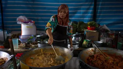 NurPhoto A lady preparing ayam rendang in Malaysia