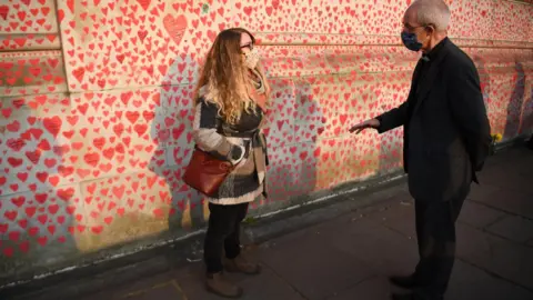 PA Media Jo Goodman speaking to the Archbishop of Canterbury next to the National Covid Memorial Wall in London