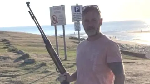 Social Media Councillor Jon Scriven's Facebook post showed him holding a gun