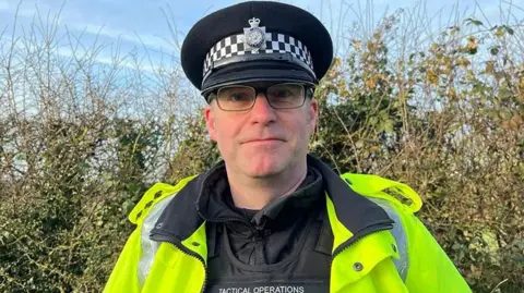 Ch Insp Matt Wilmott wearing black glasses and a hi-vi jacket with his Lancashire Police uniform