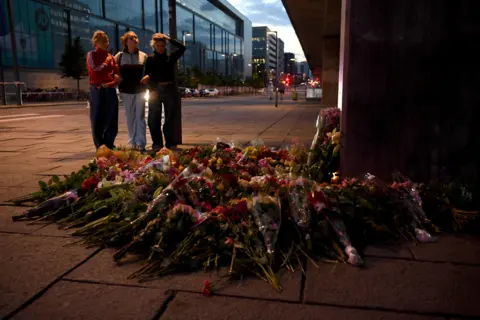 ANNEGRET HILSE/Reuters People lay flowers laid near the Field's shopping centre, a day after a shooting at the site in Copenhagen, Denmark, 4 July 2022.