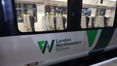 A close up of a train carriage with "London Northwestern Railway" written in green on its side.