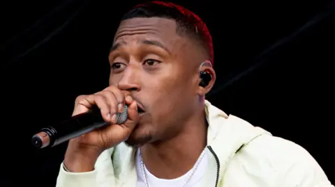A close up of the rapper Yung Filly on stage holding a microphone to his mouth as he performs.