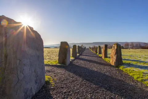 Mike Bolam An alley way of stone chips through the countryside lined with large boulders on either side