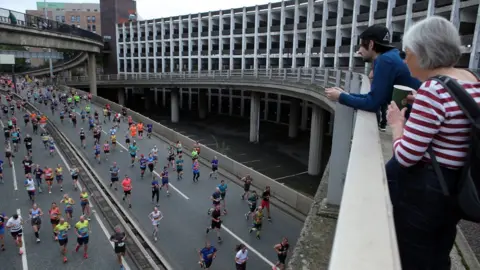 PA Media A man and woman stand on a bridge over looking the runners
