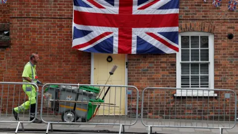 AFP/Getty Images A street cleaner walks past a house decorated in bunting and a Union flag in Windsor