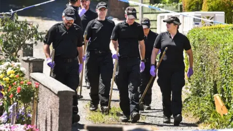 Getty Images Police forensic officers search a garden