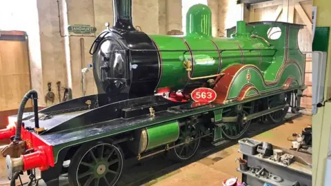 Swanage Railway Green and black steam locomotive in a workshop