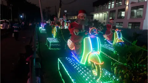 Getty Images Christmas decorations depicting Santa Clauses on scooters shown at a roundabout in Lagos, Nigeria