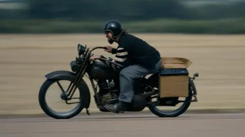 On the Roam/HBO Max Jason Momoa riding a vintage motorcycle around a track.