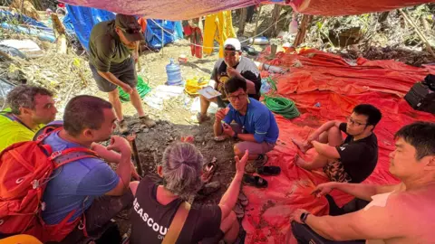 Rescuers gather at the scene in Laos to discuss fresh rescue efforts