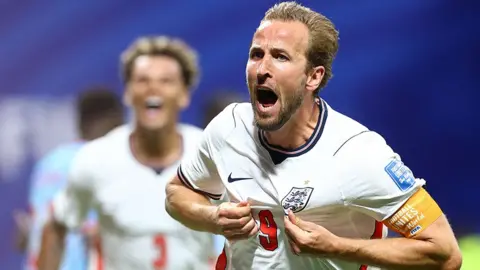 Reuters England's Harry Kane celebrates after scoring. He is holding his shirt out and shouting