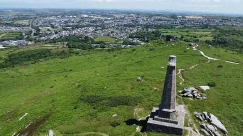 Drone shot of Carn Brea monument with Redruth in the background. 