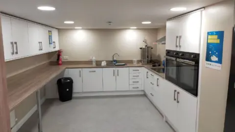 AFCF / FREEDOM OF INFORMATION A picture showing a newly installed kitchen.  It features white cupboard doors with large handles, two ovens and a fridge.