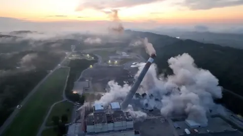 A chimney crashing to earch in a controlled demolition.