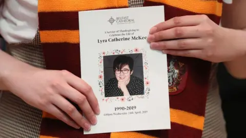 Getty Images A mourner wearing a Gryffindor scarf from the Harry Potter series holds an order of service as they arrive to attend the funeral service of journalist Lyra McKee