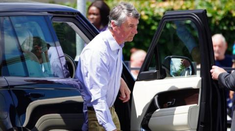 Vice Admiral Sir Tim Laurence arriving at Southmead Hospital in Bristol. He is seen stepping out of a jeep car and is wearing a shirt with no tie. 