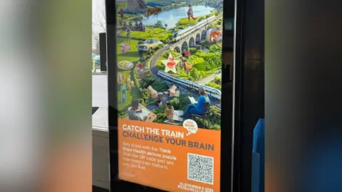 Alzheimer’s Research UK A poster of the puzzle at Didcot station. The slogan reads "Catch the train, challenge your brain".