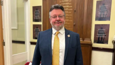 Councllor Barry Lewis stood in front of a war memorial inside county hall