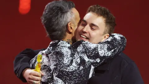 Robbie Williams hugs Sam fender