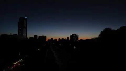 Getty Images General view of Santiago, Chile, showing buildings in almost complete darkness silhouetted against an orange sunset.