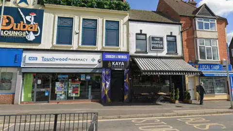 Google A view of the entrance to Kaya Lounge which is a door between a coffee shop and a pharmacy
