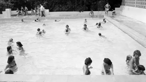 Getty Images A black and white picture of people in an outdoor pool in Wokingham in 1976.