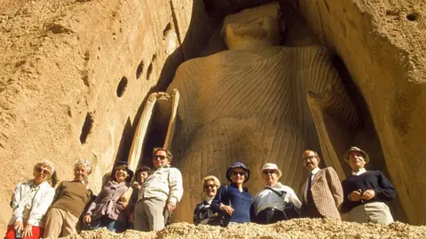 Getty Images View of Western tourists posing before the massive height of the smaller giant Buddha, known as Shamama, in Bamiyan, Hazarajat region, central Afghanistan, November, 1975.