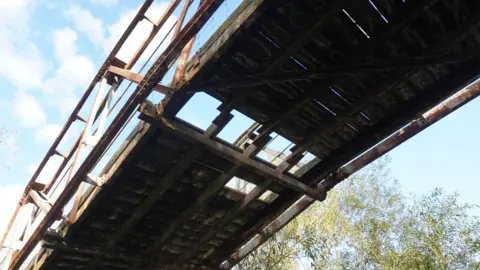 Megan McKay A view of the Works bridge at Attenborough Nature Reserve from underneath it, showing a hole in the bridge and rusting of the structure.