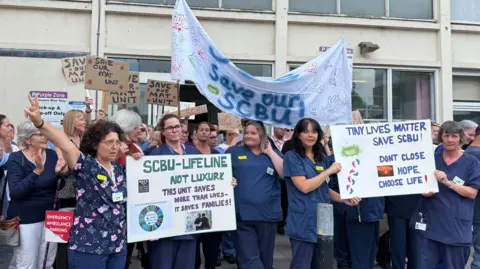 A group of people holding placards outside Yeovil District Hospital in a protest about its maternity unit closing