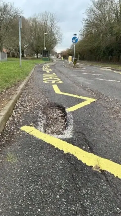 A view of Sullivan Road with a pothole and yellow road markings painted around it