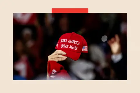 Getty Images A adjacent  up   of a idiosyncratic   holding a reddish  chapeau  that reads 'Make America Great Again'