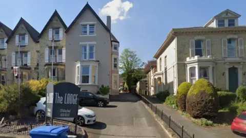 A three-storey hotel in Scarborough with a sign at the front of a car park reading The Lodge