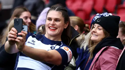 Rugby player Ilona Maher poses for a selfie with a fan.