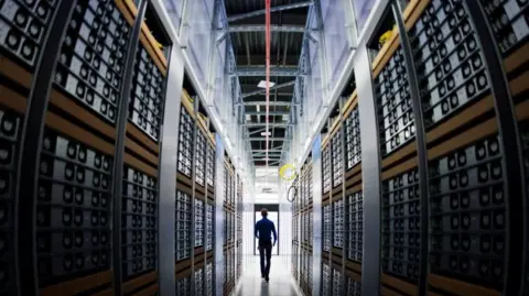 Getty Images A man walks between racks of servers in a data centre.