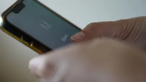 Close up image of hands on a smartphone. The number being contacted is saved as 'Mam'.