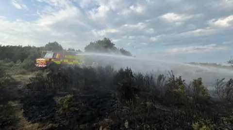 DWFRS The new Unimog spraying water in the countryside. It is a cloudy day.
