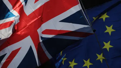 A Union flag, also known as Union Jack, left, and a European Union (EU) flag fly during a Unite for Europe march to protest Brexit in central London.
