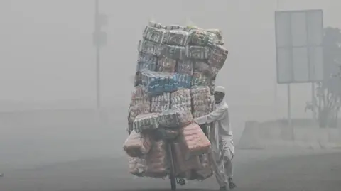 Getty Images A vendor delivers food on his bicycle cart on a smoky street in Lahore 