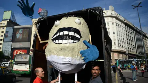 AFP Men carry a giant gnocchi dummy during a demo against the massive firing of civil servants in downtown Buenos Aires, on 29 January 2016