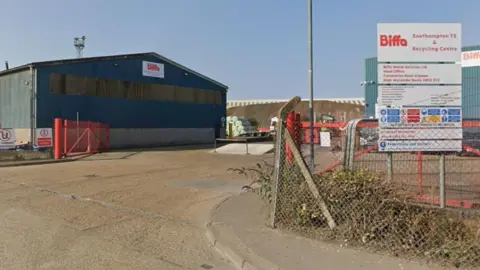 A large blue depot on an industrial estate with a Biffa sign on the gable end. A white sign with red writing, says 'Biffa Southampton TS and recycling centre'
