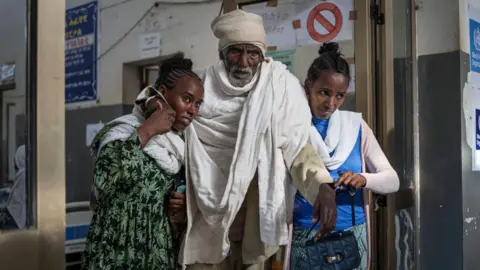 Getty Images Two women carry a patient at the emergency ward of the Suhul General Hospital in Shire on October 11, 2024. Many hospitals and clinics were targeted during the war between Tigrayan forces and the federal government that raged from November 2020 to November 2022. (Photo by Michele Spatari / AFP) (Photo by MICHELE SPATARI/AFP via Getty Images)