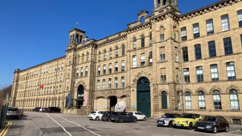 BBC A five-storey mill building made from soot-strained yellow, Yorkshire stone. 