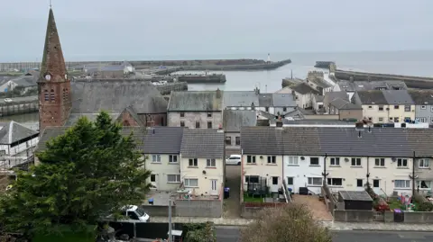 A general view of Maryport seen from above. There are houses in the foreground, with Christ Church to one side, the marina and harbour in the distance.
